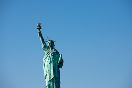 Iconic Statue of Liberty with torch against a bright blue sky, symbolizing freedom.